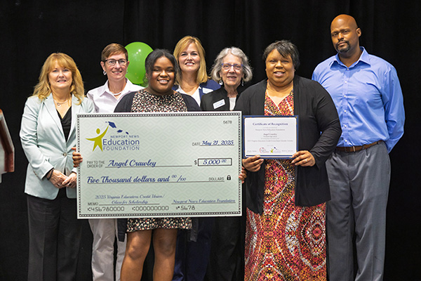 Miss Crawley accepting award check surrounded by dignitaries.